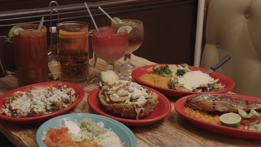 Multiple diverse dishes and drinks on a rustic restaurant table.
