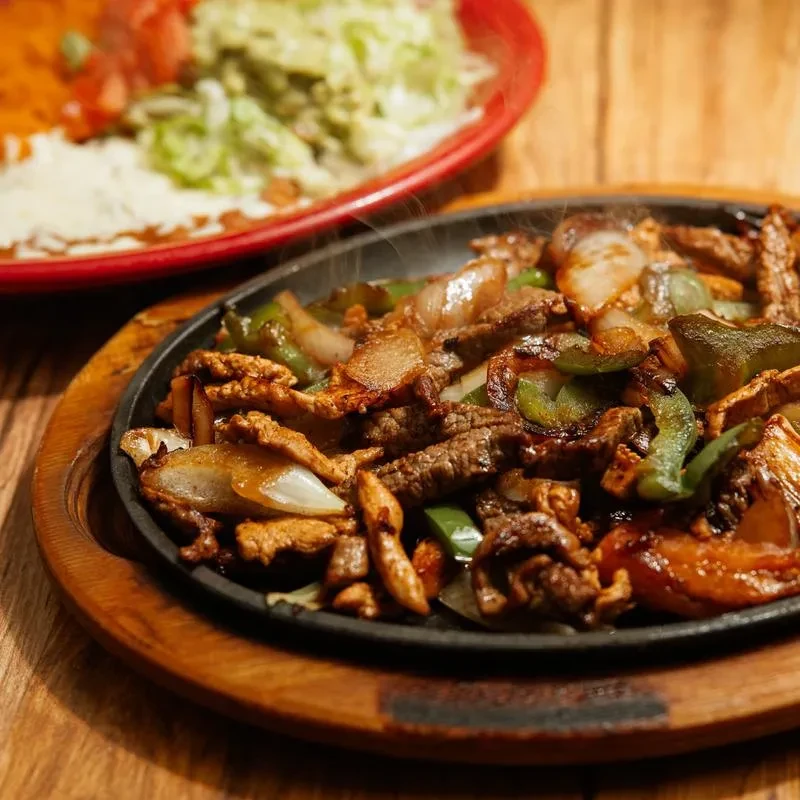 Sizzling fajitas on a cast iron skillet with visible steam.