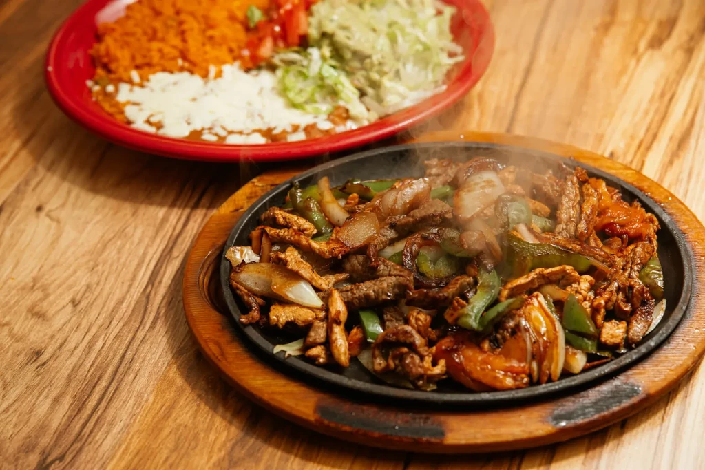 Sizzling fajitas with meat, vegetables, and Mexican side dishes.