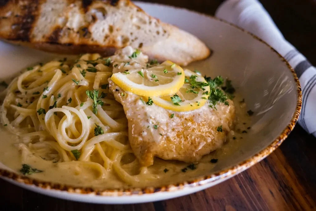 Creamy pasta, seared protein with lemon, parsley, and toasted bread.
