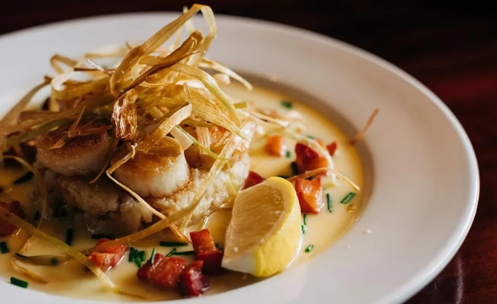 Gourmet seared scallops, risotto, crispy garnish, creamy sauce, and lemon.