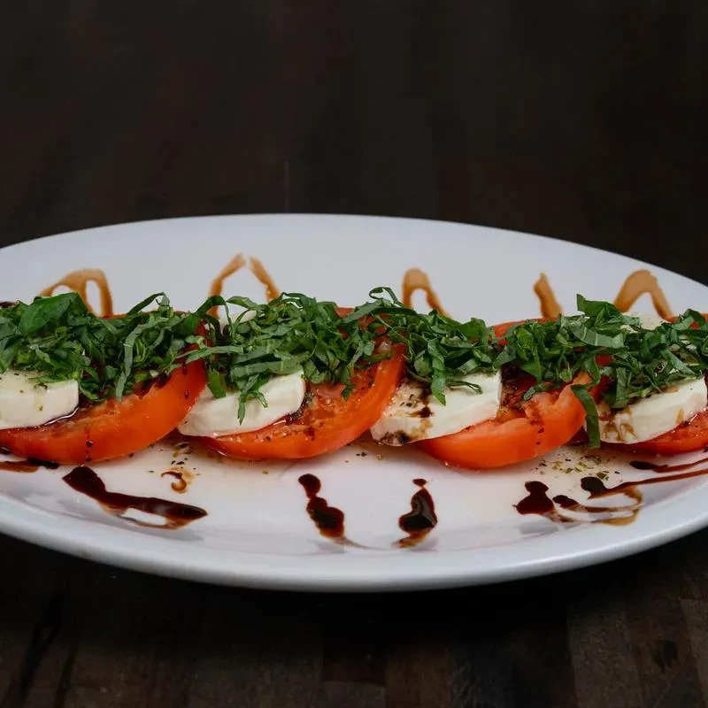 Caprese salad with sliced tomatoes, mozzarella, basil, and balsamic glaze.