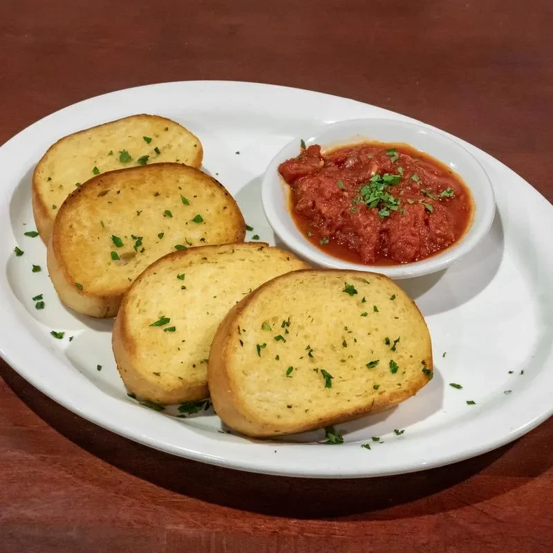 Golden-brown toast slices with herbs and chunky tomato dipping sauce.