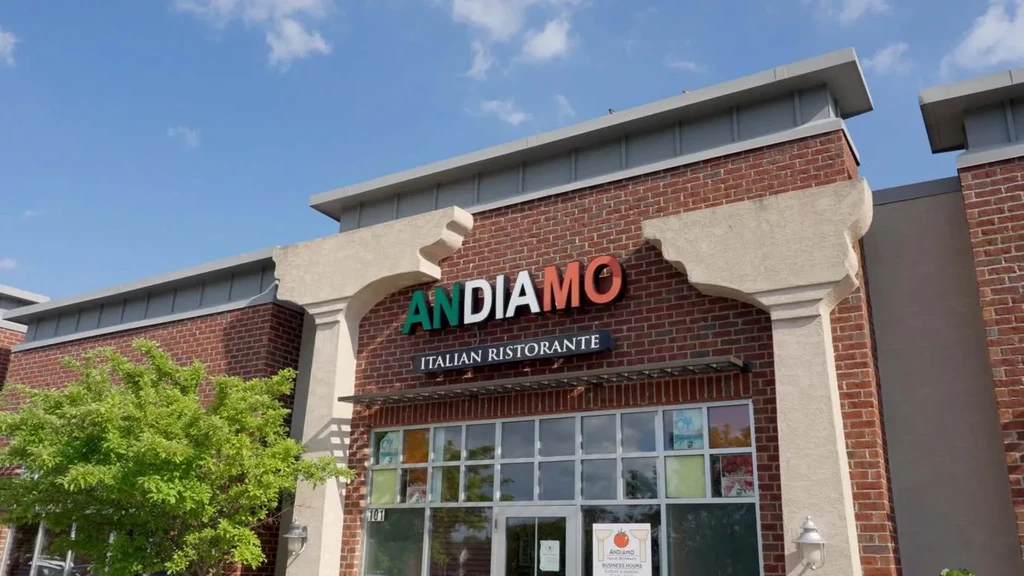 Facade of ANDIAMO Italian Ristorante, red brick, colorful sign, glass entrance.