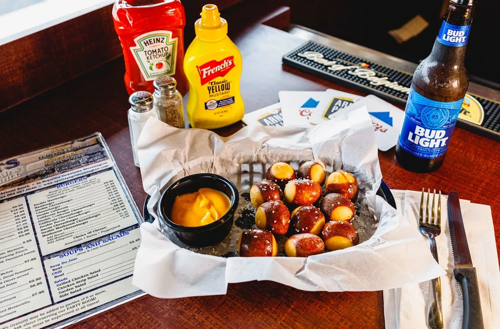 Pretzel bites with cheese dip and Bud Light on a sports bar table.