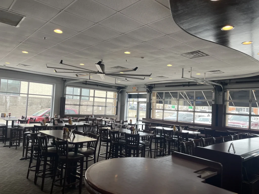 Empty restaurant interior with bar, tables, chairs, and large windows.