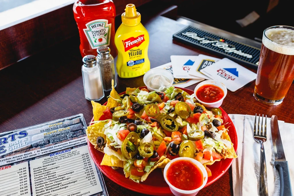 Fully loaded nachos, beer, and menu at a casual sports bar.
