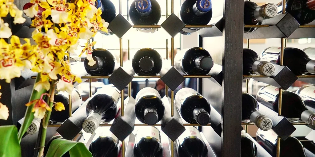 Elegant wine rack filled with dark bottles and vibrant orchids.