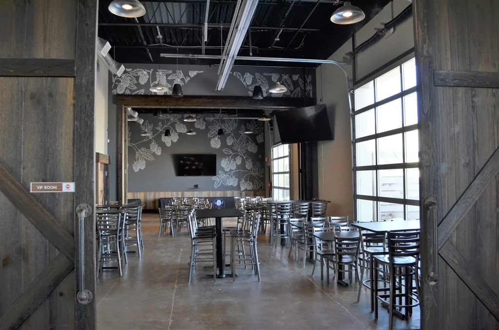 Empty modern industrial restaurant with rustic barn doors and VIP ROOM sign.