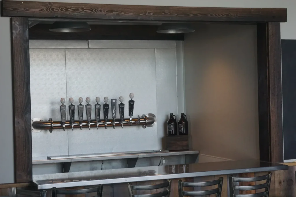 Industrial bar with ten beer taps, growlers, and metal stools.
