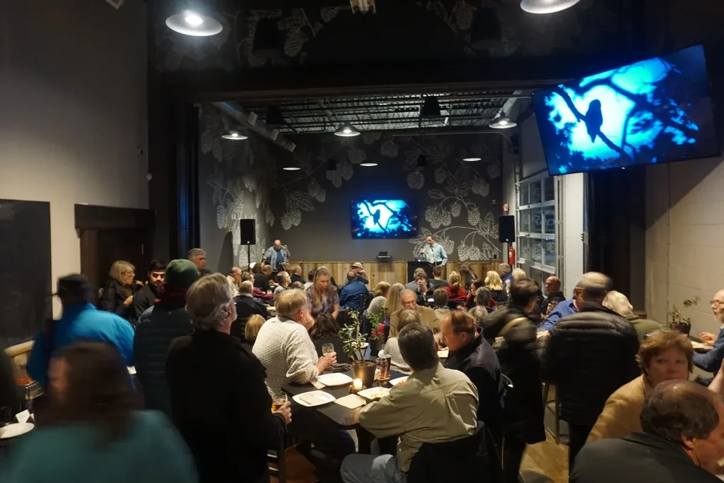 A crowded modern industrial-chic event space with a stage.