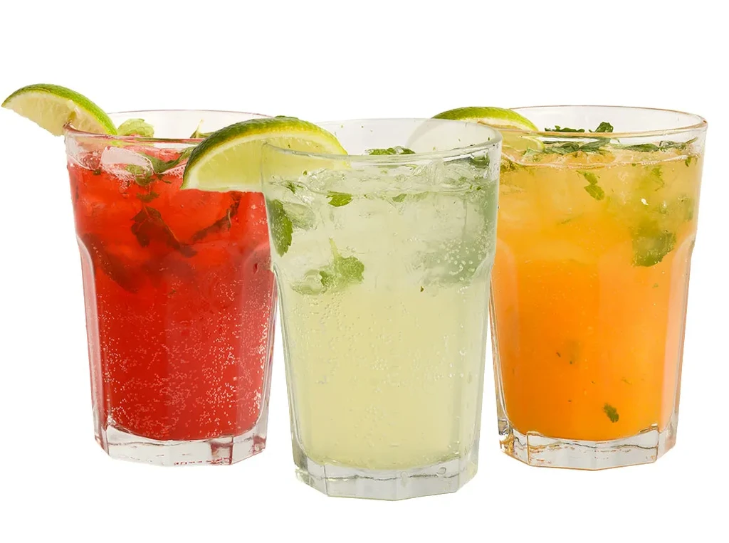Three colorful iced drinks with mint and lime on white background.