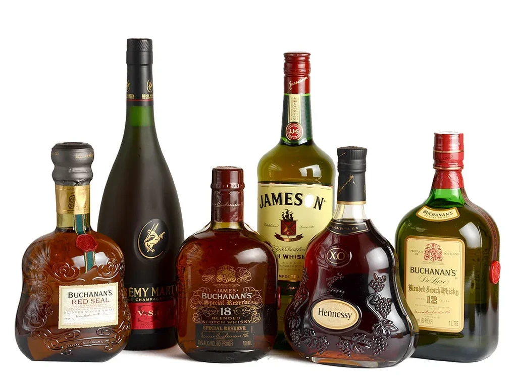 Six different bottles of whisky and cognac on white.