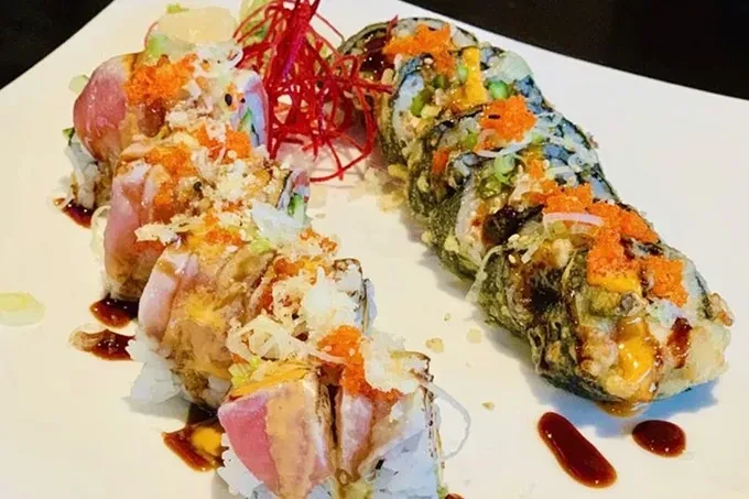 Sushi plate with tuna rolls, deep-fried rolls, and garnishes.