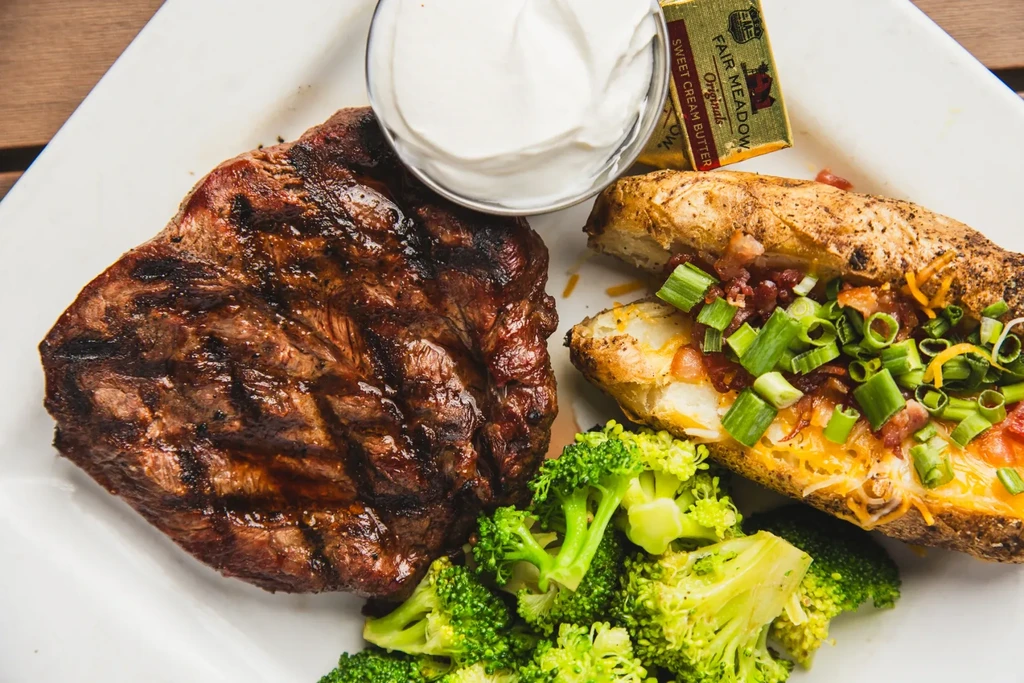 Grilled steak, loaded baked potato, broccoli, sour cream, and butter.