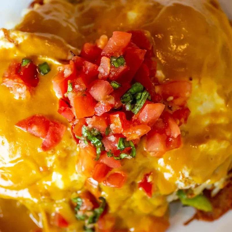 Close-up of a brunch dish with golden sauce and tomato-herb topping.