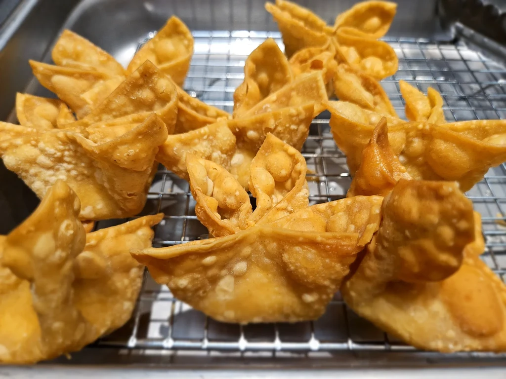 Fried golden-brown wonton-like pastries cooling on a metal rack.