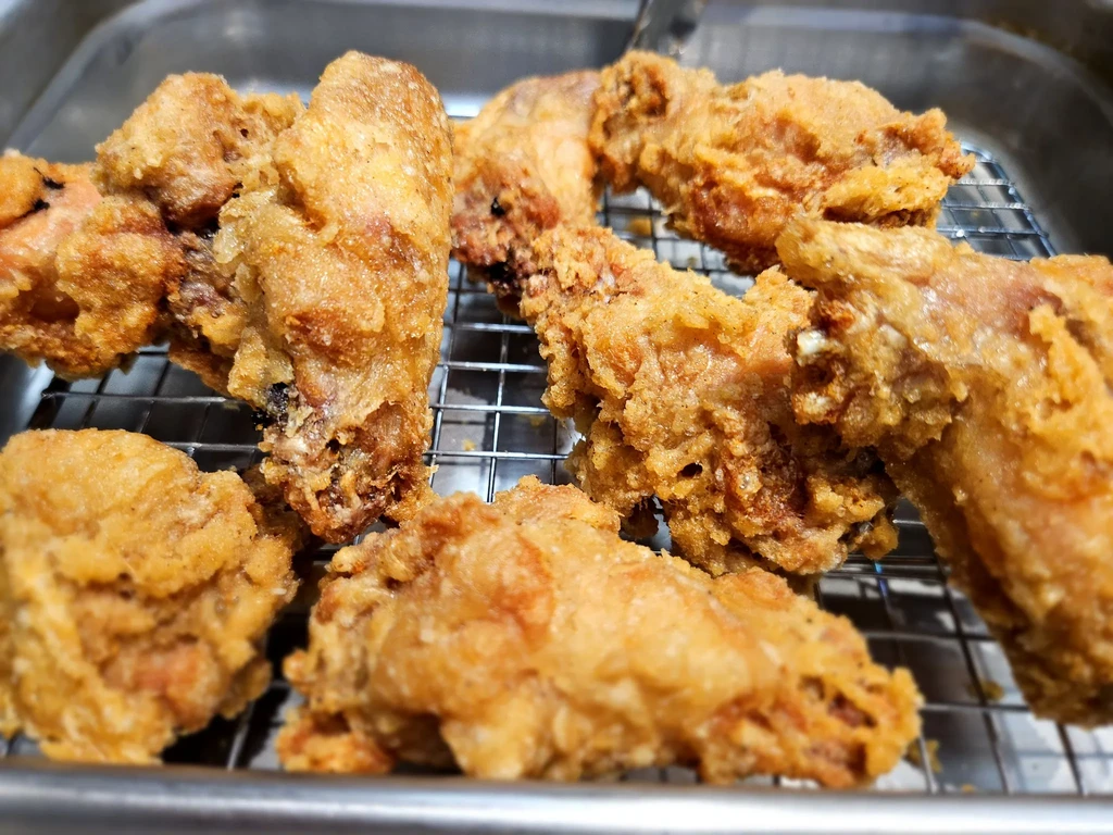 Several pieces of crispy fried chicken on a metal cooling rack.
