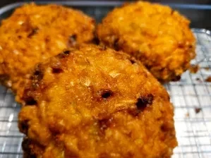 Three round, crispy golden-brown fritters on a metal rack.