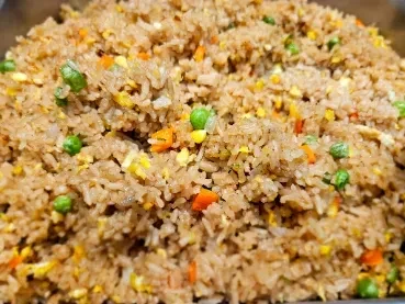 Top-down view of stir-fried rice with peas, carrots, and scrambled egg.