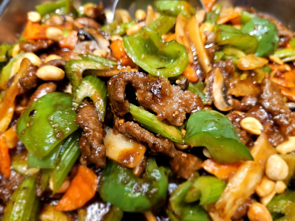 Colorful stir-fry with beef, vegetables, peanuts, and dark sauce.