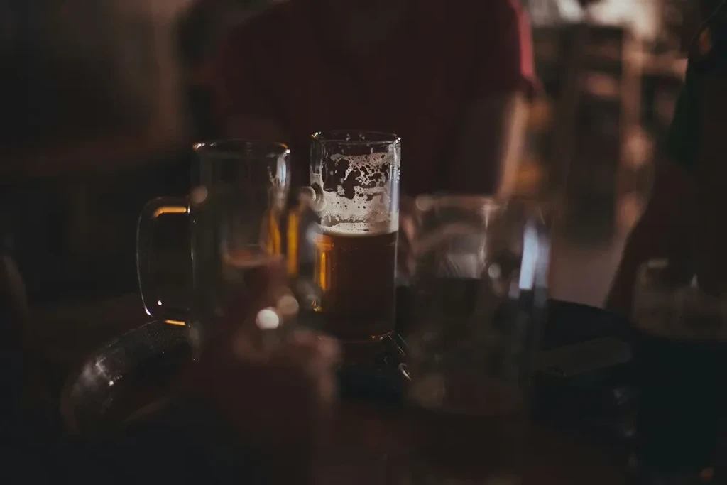 Partially consumed beer and empty glasses on a dimly lit bar table.