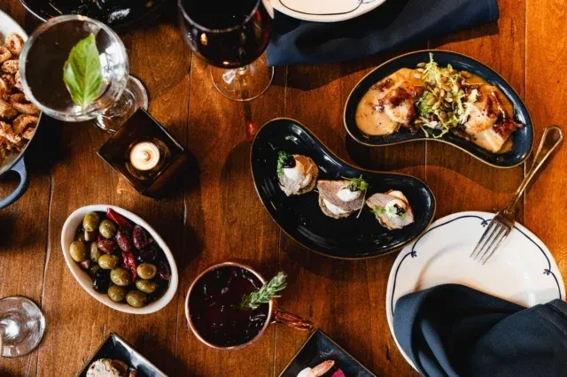 Overhead of a rustic table set with various gourmet dishes and drinks.