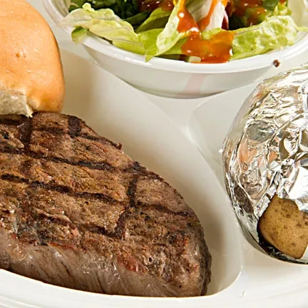 Grilled steak, baked potato, green salad, and bread on white plate.