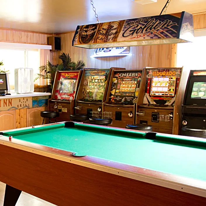 A bar game room with a pool table and arcade machines.