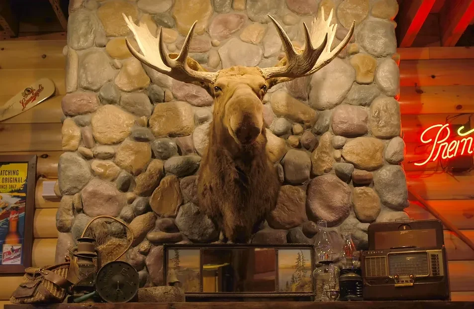 Large taxidermied moose head on stone fireplace in a rustic lodge.