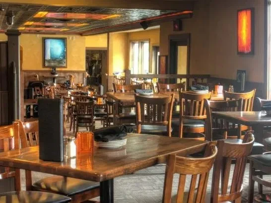 Warm, empty restaurant dining room with set wooden tables and chairs.