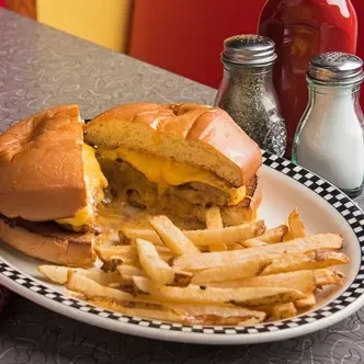 Cheesy sandwich, fries, and shakers on a checkered diner plate.