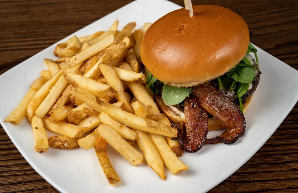 Gourmet burger with bacon, melted cheese, and hand-cut french fries.