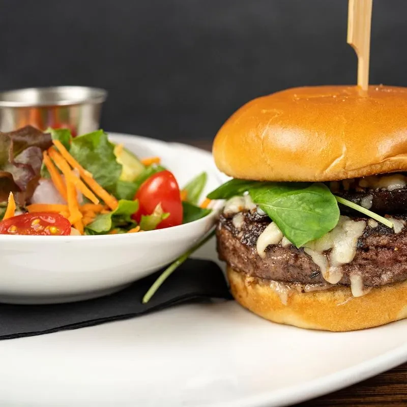 Double-patty burger with cheese, spinach, and a mixed green side salad.