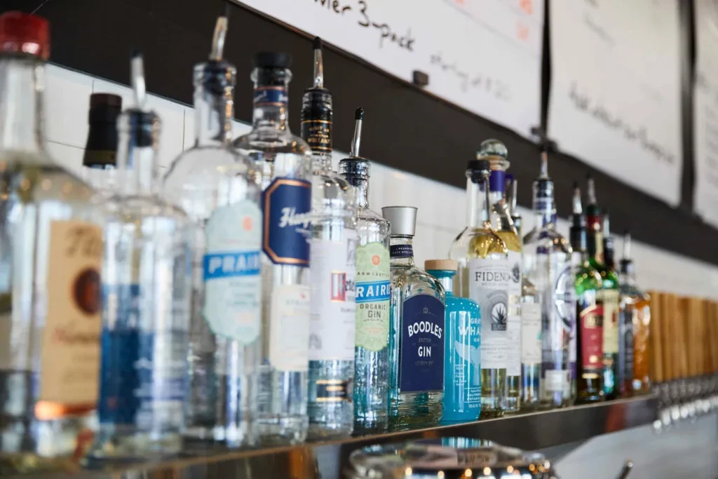 A well-stocked bar shelf with various liquor bottles and beer taps.