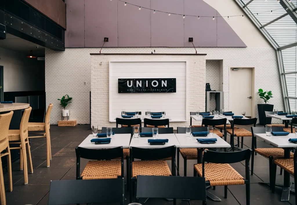 Union Rooftop Kitchen + Bar interior with set tables, glass ceiling.