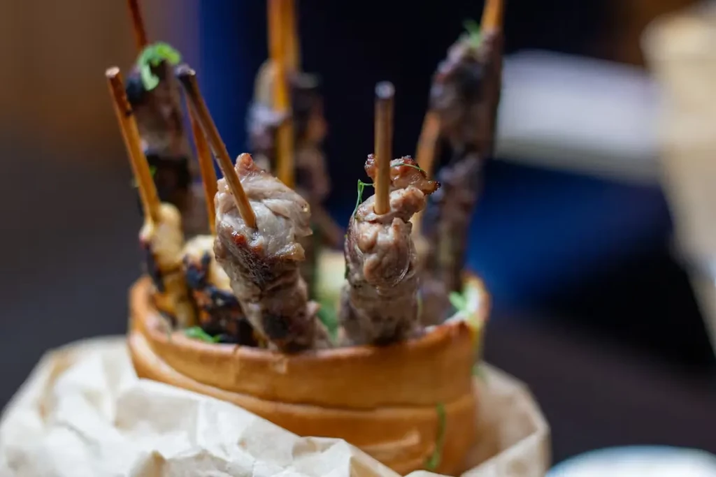 Grilled skewers with char marks and herbs in a rustic bread bowl.