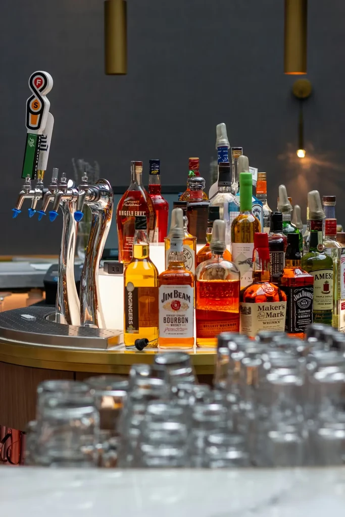 Well-stocked modern bar with liquor bottles, beer taps, and glassware.
