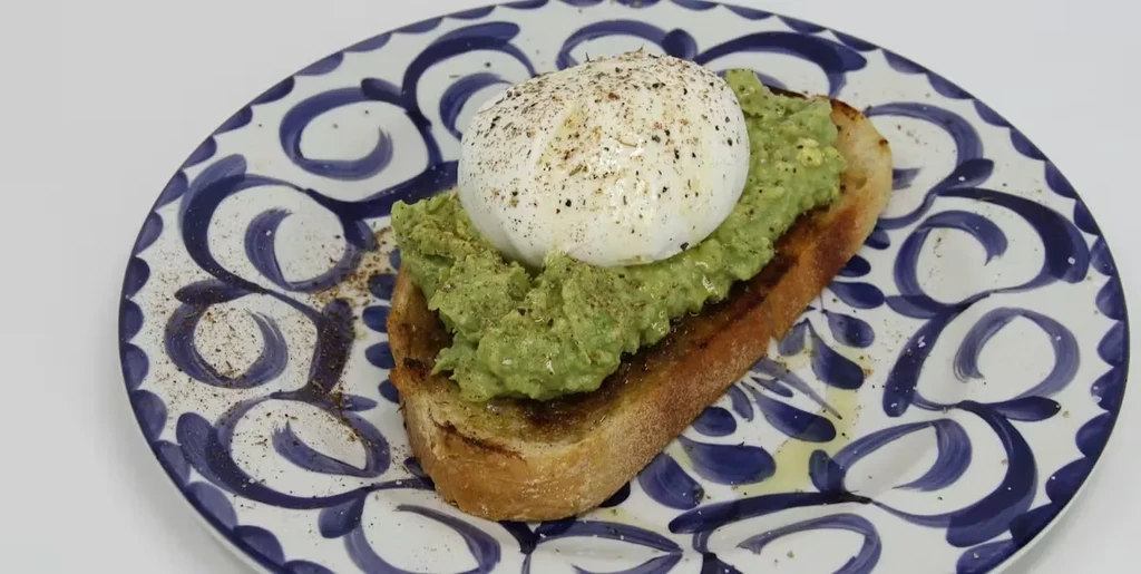 Avocado toast topped with a poached egg on a patterned plate.