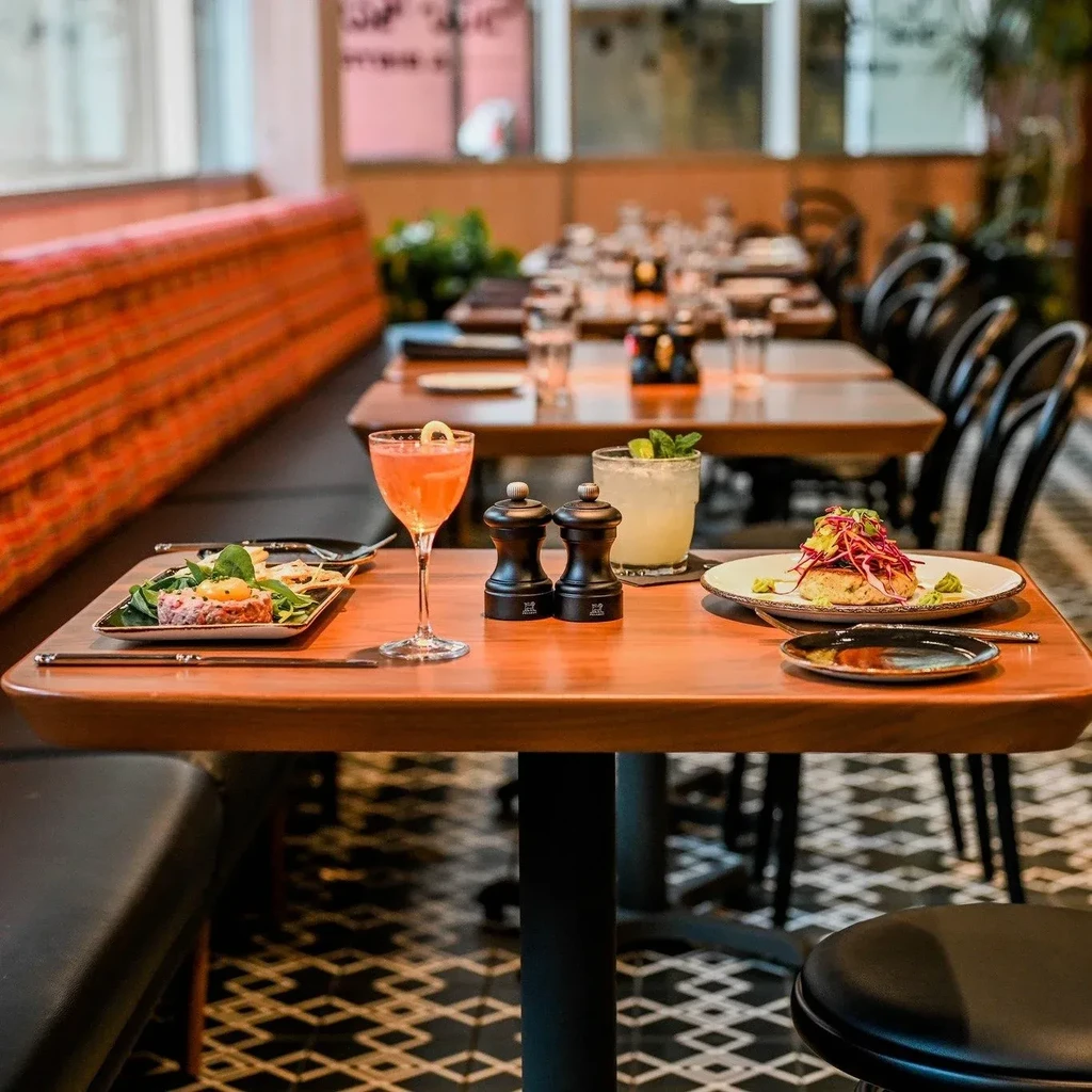 Restaurant table with an appetizer, a main course, and two cocktails.
