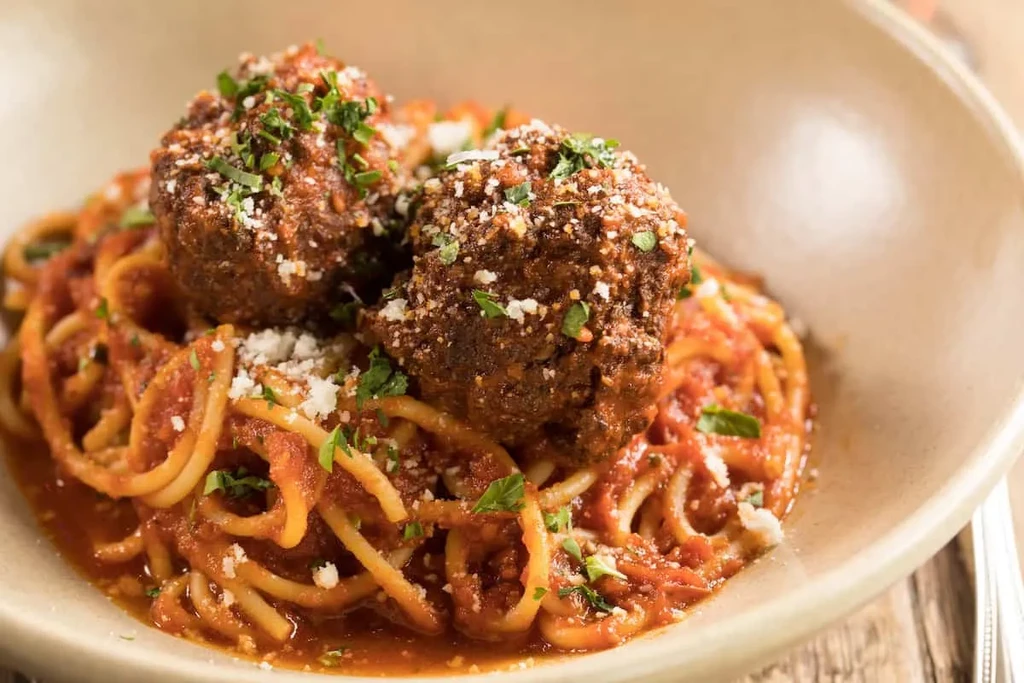 Close-up of spaghetti and meatballs with marinara, Parmesan, and parsley.