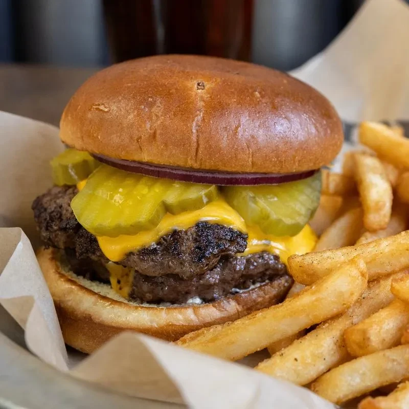 A double cheeseburger with melted cheese, pickles, and golden french fries.
