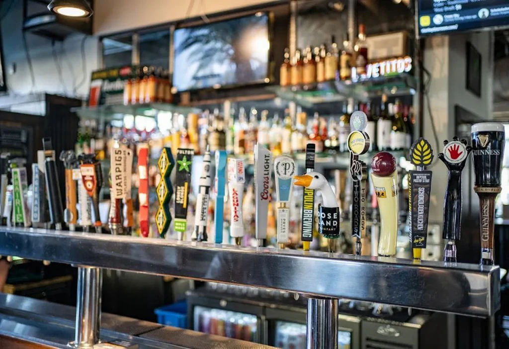 Foreground view of diverse beer tap handles on a polished bar system.