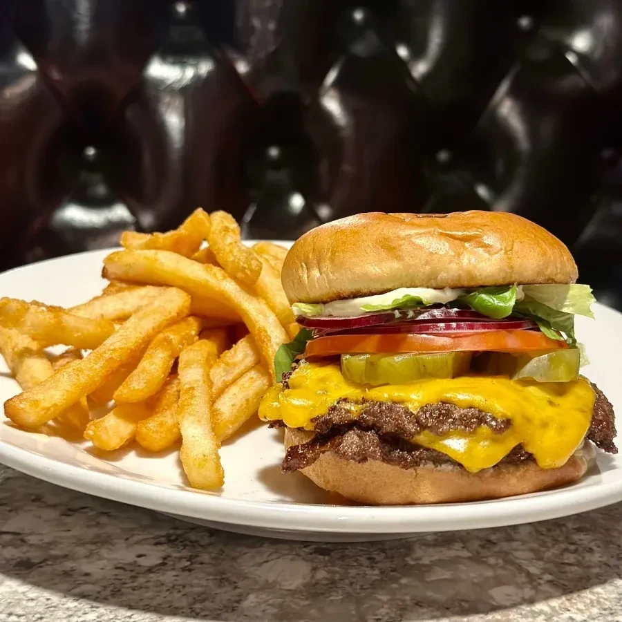 Close-up: Cheeseburger with melted cheese, vegetables, and crinkle-cut fries.