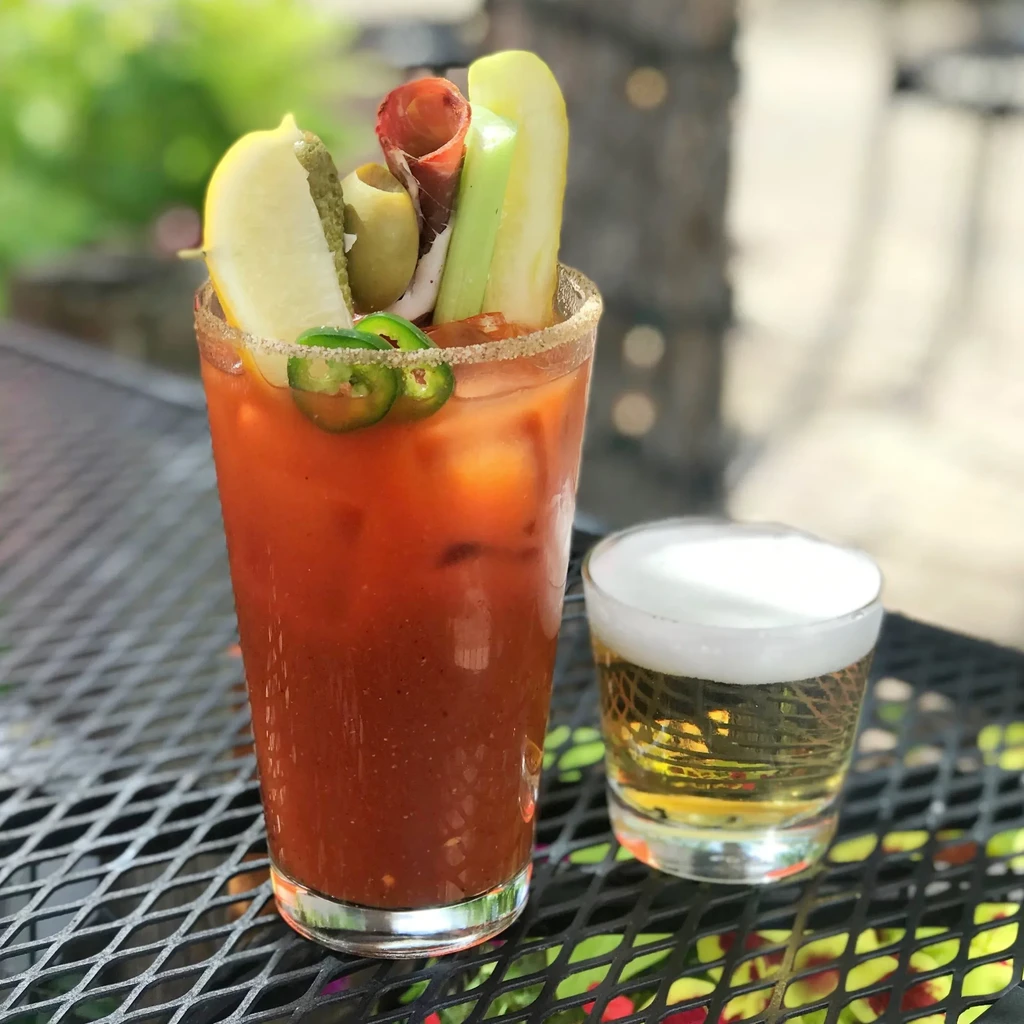 Elaborately garnished Bloody Mary with a beer chaser on an outdoor table.