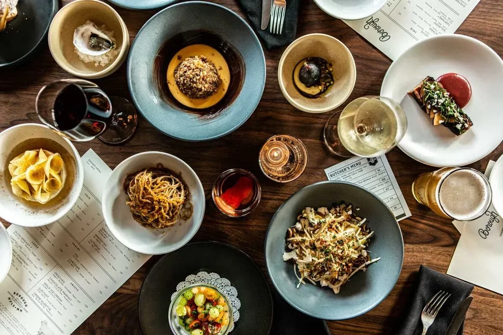 Gourmet dishes, wines, and menus arranged on a dark restaurant table.