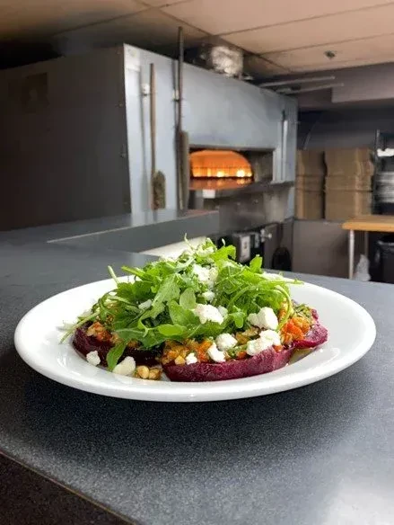 Purple vegetable dish with arugula and cheese in a commercial kitchen.