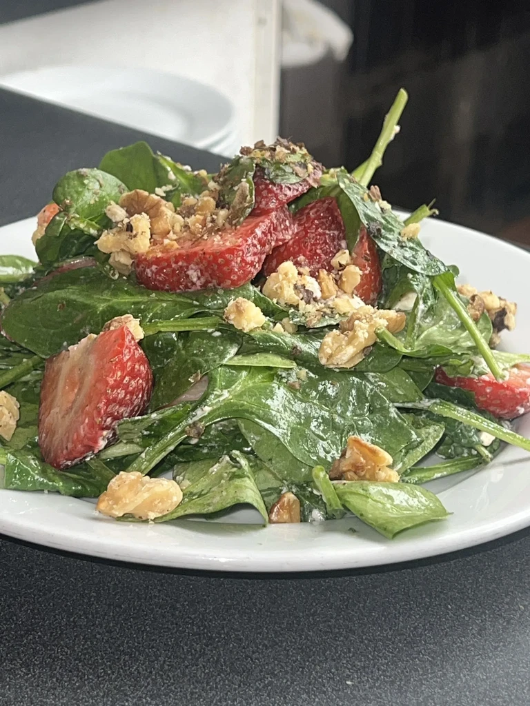 Close-up of spinach, strawberry, and walnut salad.