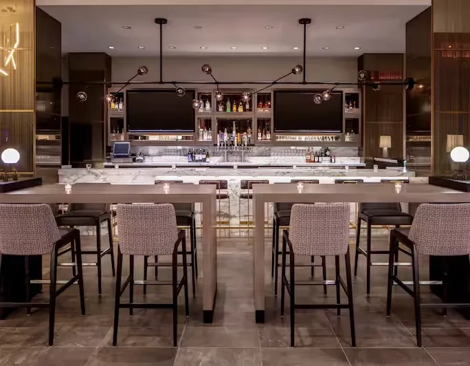 An empty, modern bar lounge with white marble bar and communal tables.