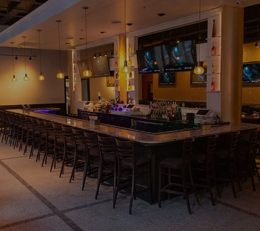 Empty, sophisticated bar with granite counter, stools, and warm lighting.